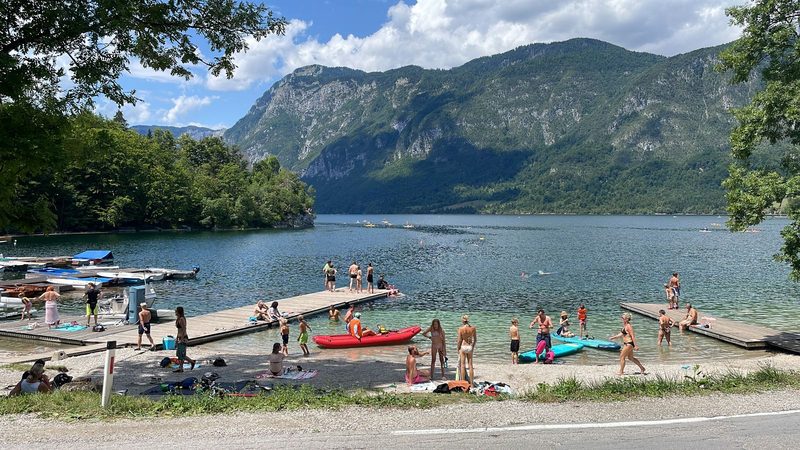 Lake Bohinj near Ribčev Laz: jetties, swimmers and SUP paddlers, behind the mountains